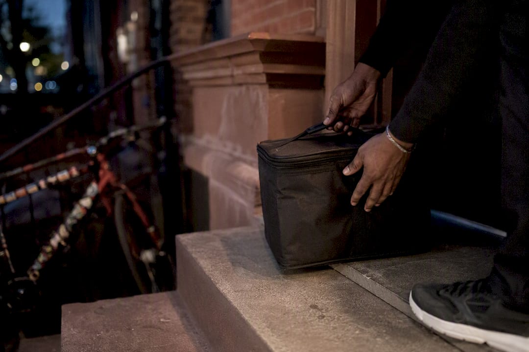 Hands placing cannabis delivery bag on NYC doorstep