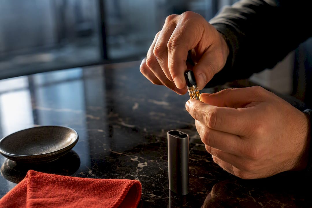 Hands gently warming a clogged vape cartridge