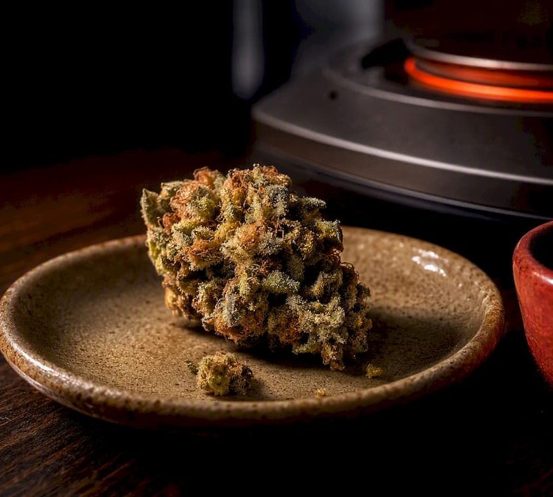 Resin-coated cannabis fragment under gentle heat