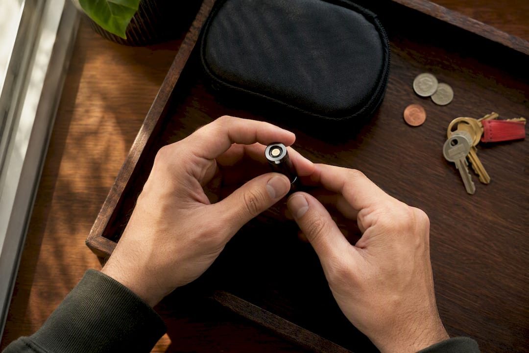 Hands inspecting battery beside separated metal objects